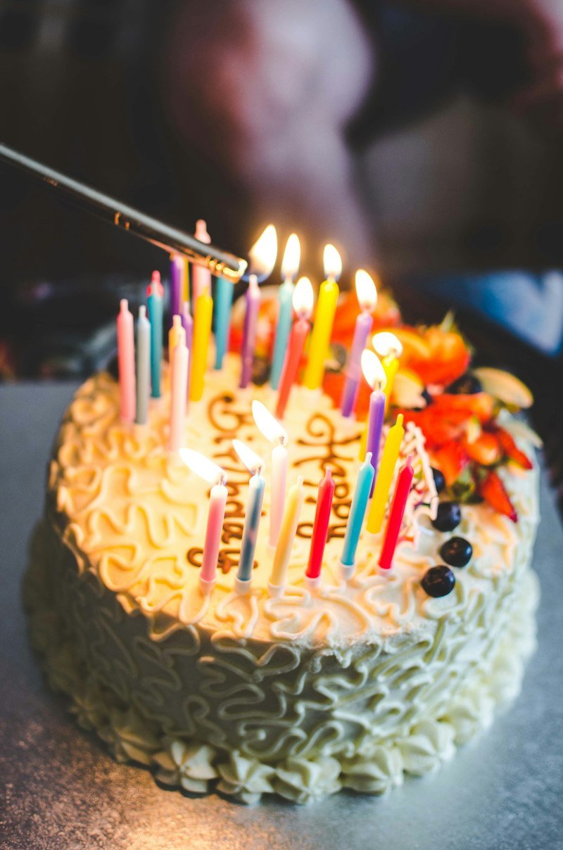 Birthday cake with colourful candles being lit for a celebration