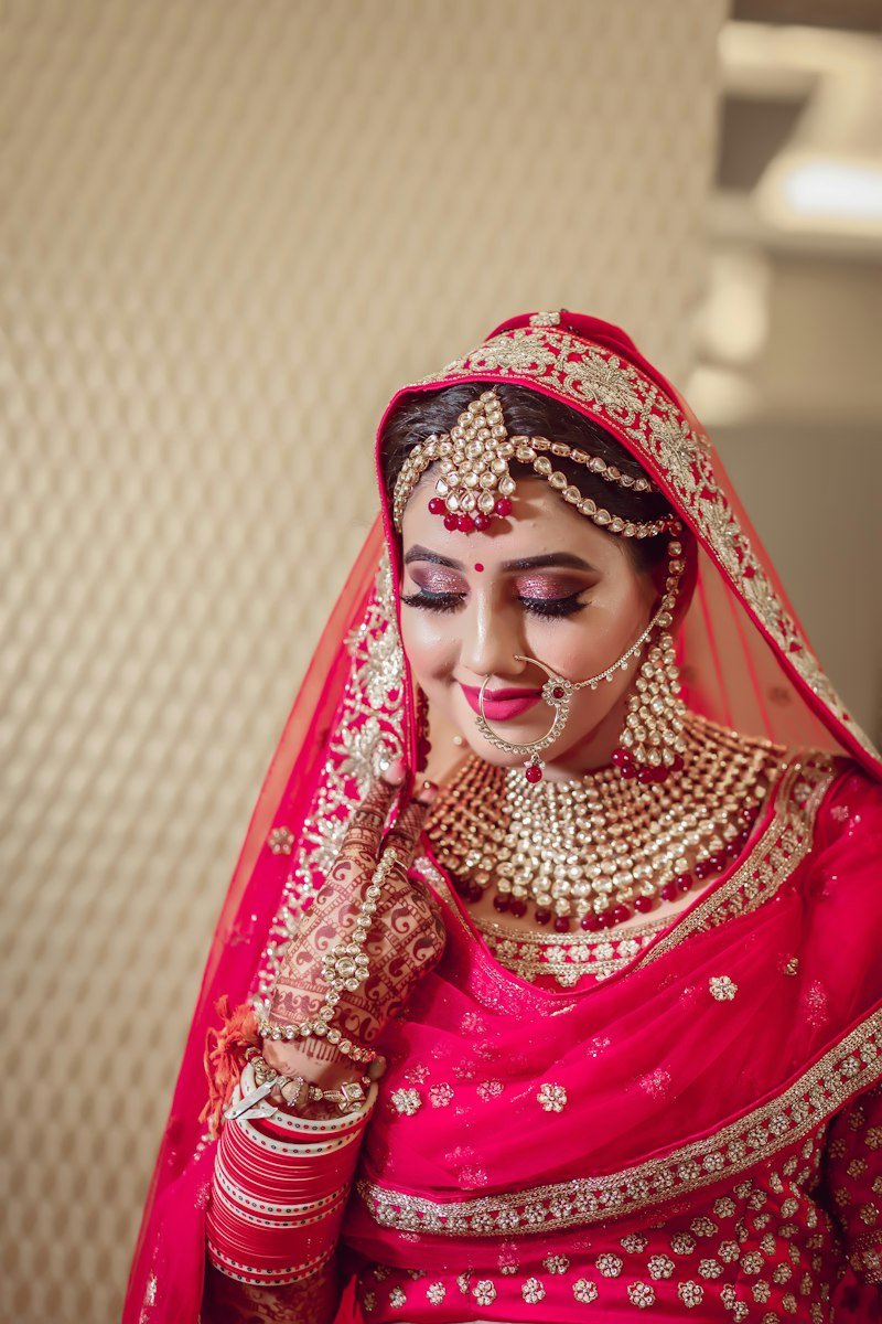 Indian bride in traditional red lehenga with gold jewellery and mehendi